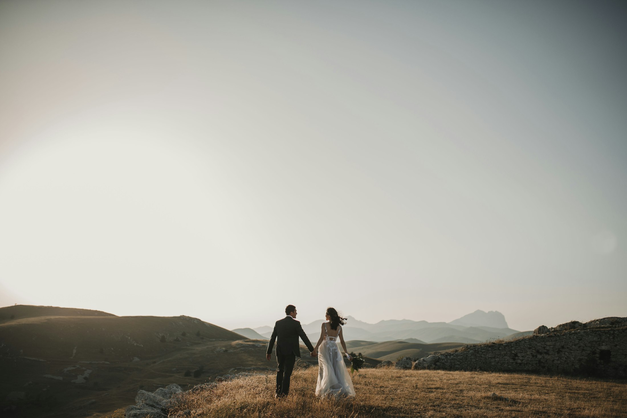 Bride and groom walking through the hills of Northern BC at dusk